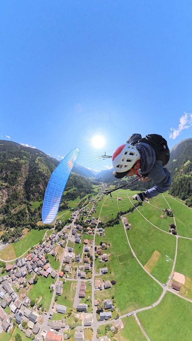 Olly paragliding above the village and fields of the Val de Bagnes