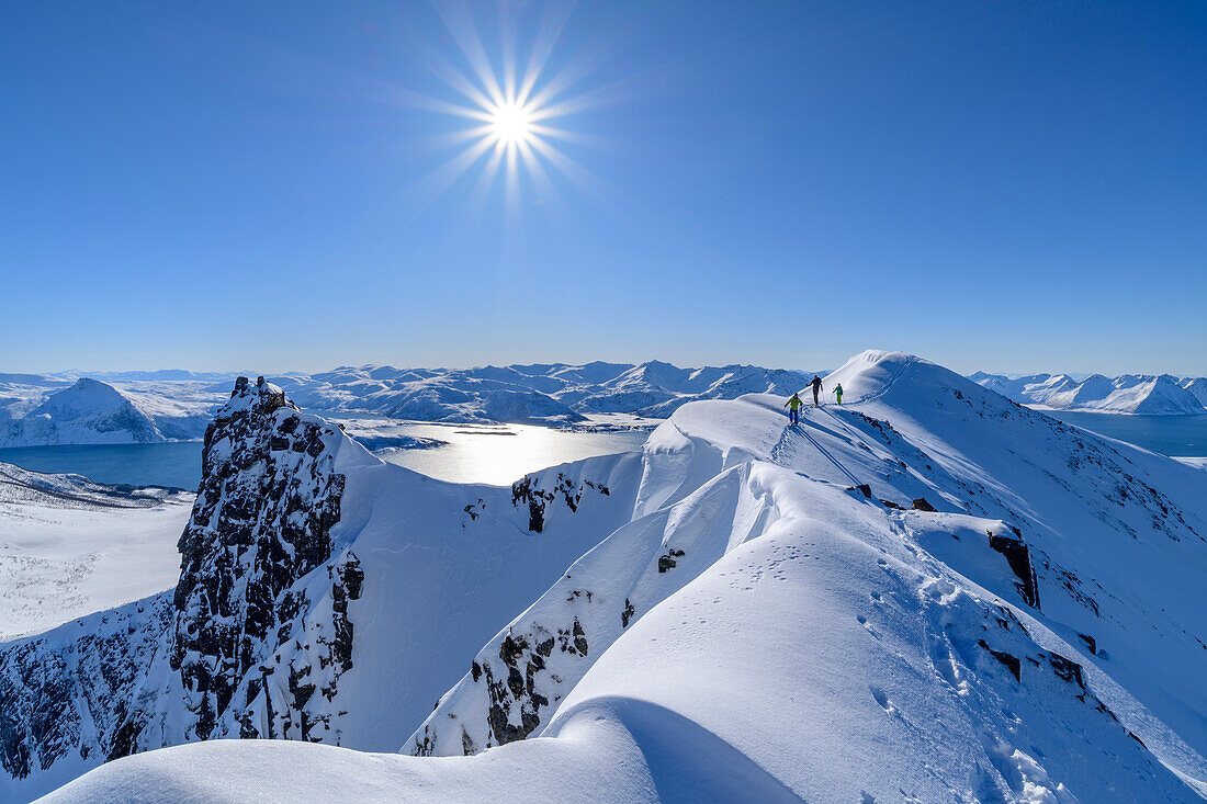 Ski tourers on a snowy ridge above the fjords near Tromsø